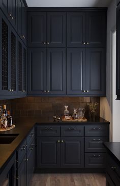 a kitchen with dark blue cabinets and wood flooring is pictured in this image, there are bottles on the counter