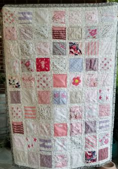 a quilt is hanging on the side of a wall in front of a potted plant