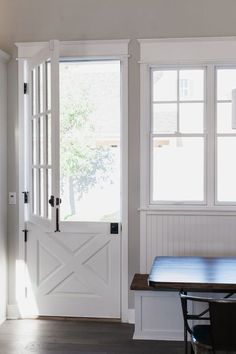 an empty room with a table and two doors that are open to let in light