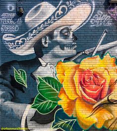 a mural painted on the side of a building with a yellow rose in front of it