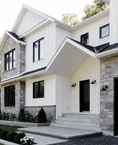 a white house with black windows and stone steps leading up to the front door area