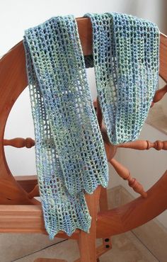 a blue crocheted scarf hanging from a wooden chair