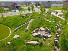 an aerial view of a grassy area with rocks and stones in the center, surrounded by houses