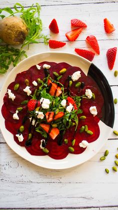 a white plate topped with beets, feta cheese and green garnish