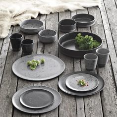 the table is set with dishes, cups and bowls on it's wooden deck