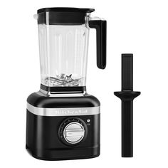 a blender sitting next to a brush on top of a white surface with a black handle