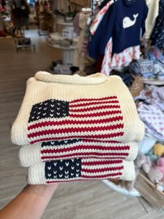 a hand holding sweaters with an american flag on them