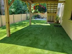 an outdoor patio with artificial grass and wooden pergols on the side of it