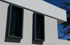 two windows on the side of a white building