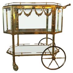 an antique brass serving cart with glass shelves