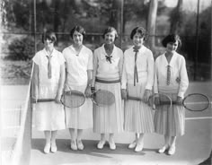 black and white photograph of four women holding tennis rackets