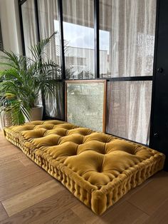 a large yellow mattress sitting on top of a hard wood floor next to a window