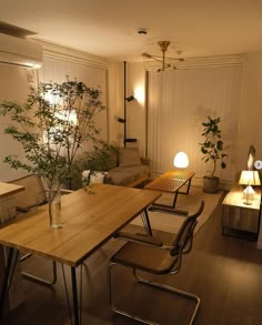 a living room filled with furniture and a wooden table surrounded by plants in vases