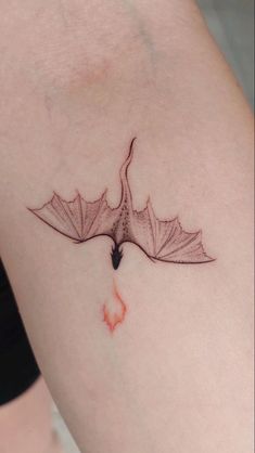 a small tattoo on the arm of a woman's leg with a bird flying over it