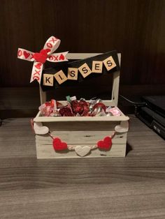 a wooden box filled with valentine's candy and candies sitting on top of a table