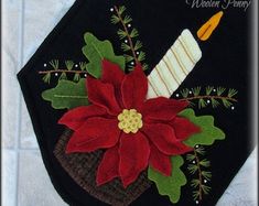 a christmas decoration with poinsettia and holly leaves on a black pot holder