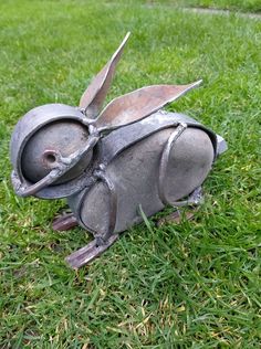 a metal object sitting in the grass with scissors sticking out of it's mouth