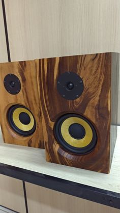 two speakers sitting on top of a wooden shelf