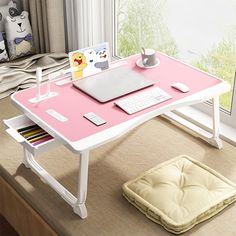 a computer desk with a laptop on it and a dog bed under the desk next to it