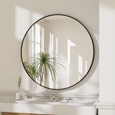 a round mirror hanging on the wall above a sink in a room with white walls