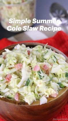 a wooden bowl filled with coleslaw on top of a red cloth next to a spoon