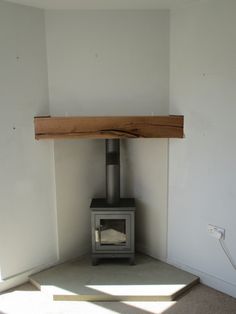 a wood burning stove in the corner of a room with white walls and flooring