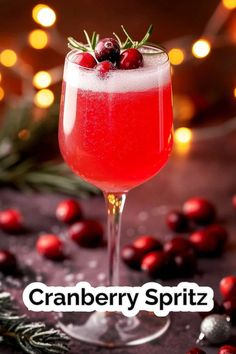 the cranberry spritz is garnished with fresh berries and rosemary