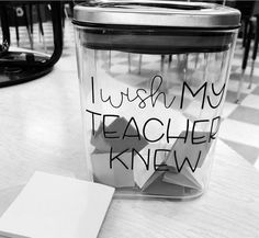 a glass jar with writing on it sitting on a table next to a notepad