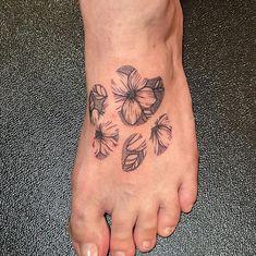 a person has a tattoo on their foot with flowers and leaves around the foot area