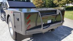 the back end of a truck parked in a parking lot next to some trees and grass