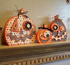 three decorated pumpkins sitting on top of a mantle