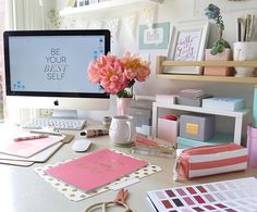 a desktop computer sitting on top of a desk next to a vase filled with flowers