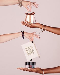 four hands reaching out to each other holding a box with nail polishes on it