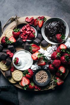 a plate with strawberries, cream and chocolate on it next to some crackers