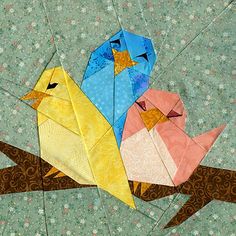 two origami birds sitting on top of a tree branch, one is yellow and the other is blue