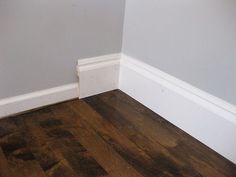 an empty room with hard wood flooring and white trim on the walls, painted gray