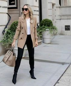 a woman is walking down the street with her hand in her pocket and wearing black boots