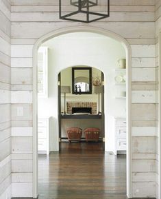 an archway leading to a living room with chairs and a mirror on the wall above it