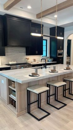 a large kitchen with black cabinets and white counter tops is pictured in this image, there are four stools at the center of the island