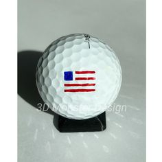 a golf ball with the american flag painted on it's side, sitting on a black stand