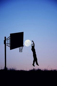 a person jumping up into the air to dunk a basketball in front of a full moon