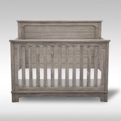 a wooden crib with white sheets on it