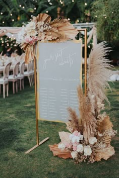 a sign that is sitting in the grass next to some flowers and pampaste