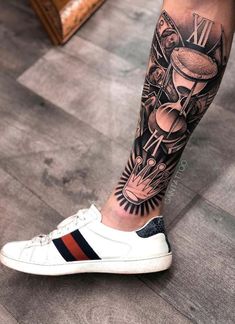 a person with a tattoo on their leg wearing white tennis shoes and black and red striped socks