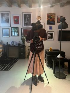 a woman holding a camera in front of a tripod