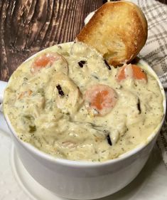 a white bowl filled with soup next to a piece of bread on top of a table