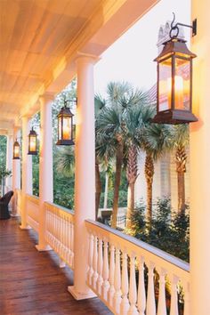 the porch is lined with white pillars and lanterns on each side, along with palm trees