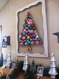 a christmas tree made out of ornaments is displayed in front of a framed photo on the wall