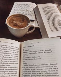 an open book sitting on top of a table next to a cup of coffee