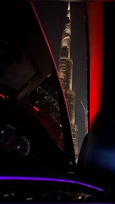 the burj tower is lit up at night in this photo from inside a car